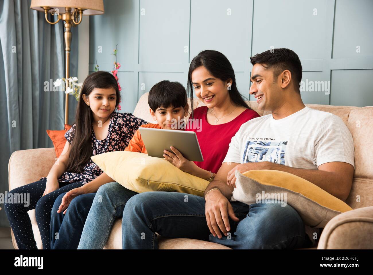 Indische Familie sitzt auf dem Sofa und mit Smartphone, Laptop oder Tablet, Film oder Surfen im Internet Stockfoto