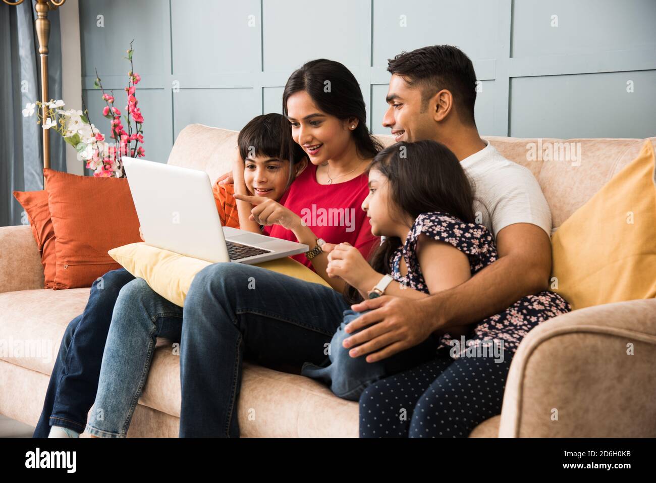 Indische Familie sitzt auf dem Sofa und mit Smartphone, Laptop oder Tablet, Film oder Surfen im Internet Stockfoto