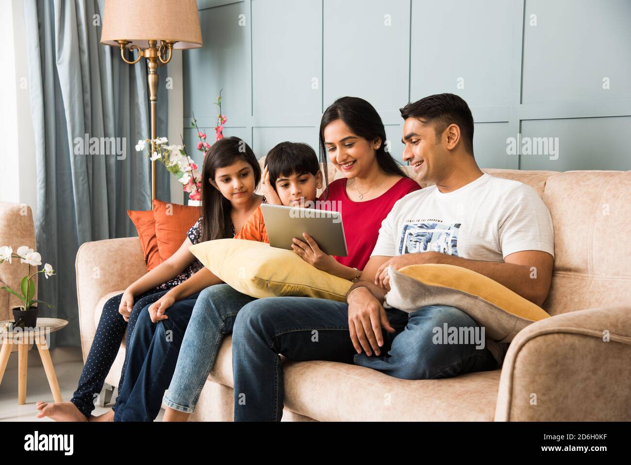 Indische Familie sitzt auf dem Sofa und mit Smartphone, Laptop oder Tablet, Film oder Surfen im Internet Stockfoto