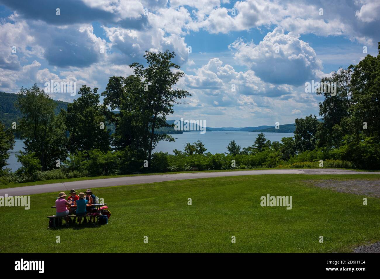 Cooperstown, NY/USA - 15. Aug 2020: Zwei ältere Paare genießen ihr Mittagessen an einem Picknicktisch, während sie den Glimmerglass State Park mit Blick auf Otsego besuchen Stockfoto