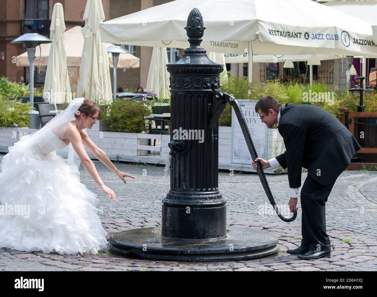 Ein Brautpaar pumpt Wasser aus dem alten Brunnen in der Altstadt von Warschau in Polen. Stockfoto