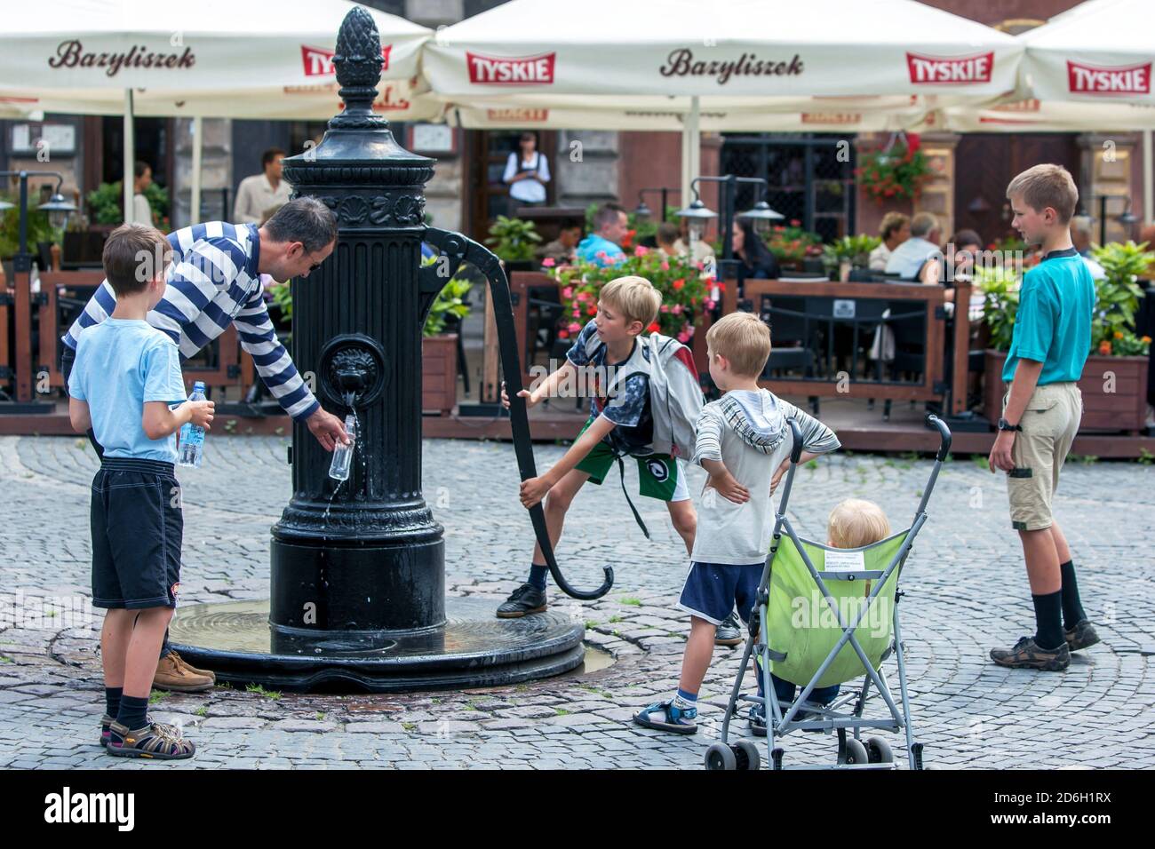 Ein Junge pumpt den alten Brunnen in der Altstadt von Warschau in Polen. Stockfoto