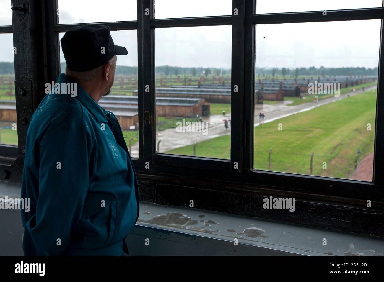 Ein Mann blickt vom Fenster im Zugturm über die Kaserne des Staatlichen Museums Auschwitz-Birkenau bei Oswiecim in Polen. Stockfoto