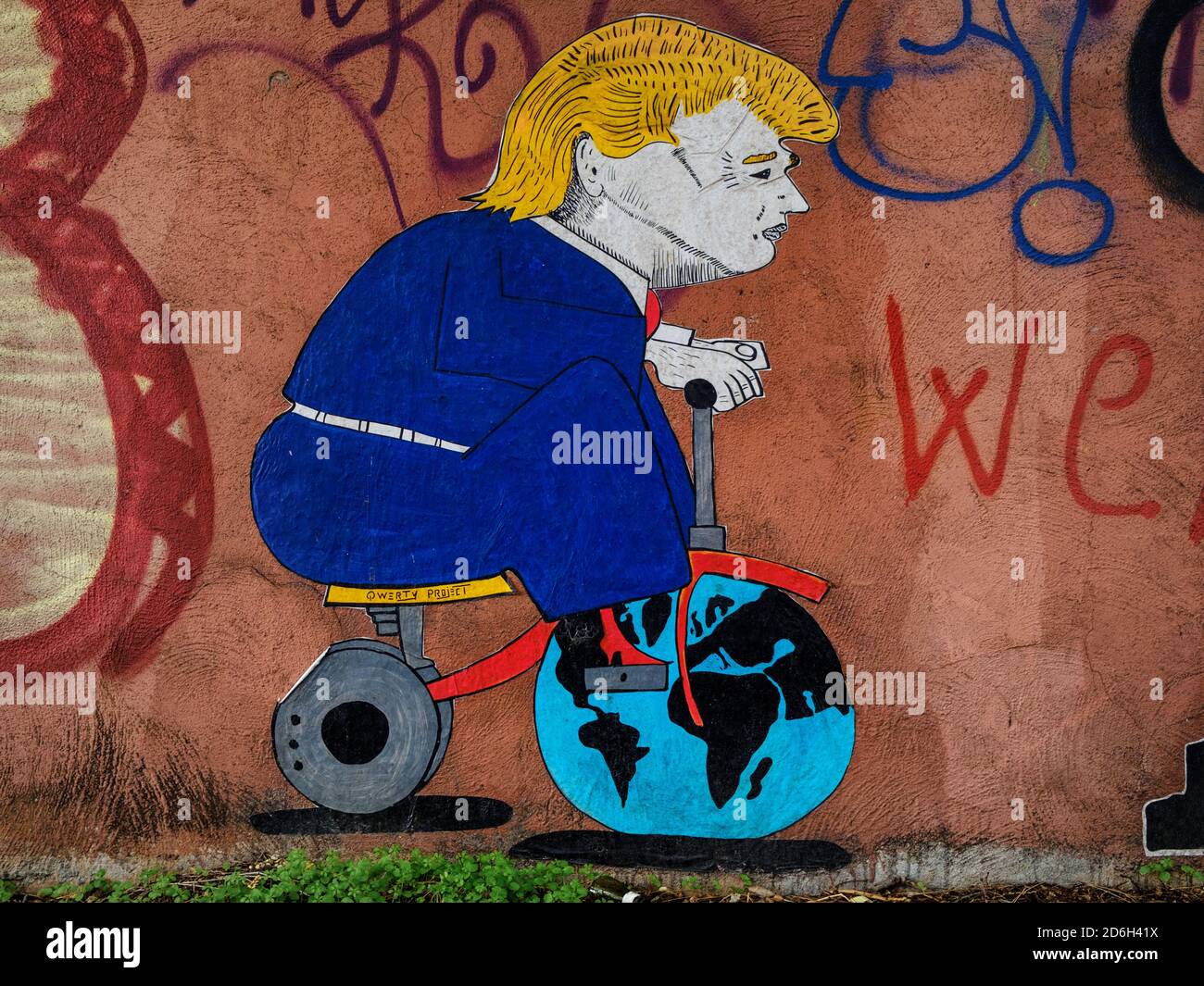 Wandkunst, die Donald Trump darstellt, der mit der Erde spielt wie ein Kind mit seinem Spielzeugfahrrad, Street Art von QWERTY Stockfoto