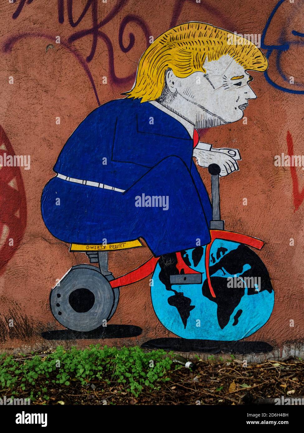 Wandkunst, die Donald Trump darstellt, der mit der Erde spielt wie ein Kind mit seinem Spielzeugfahrrad, Street Art von QWERTY Stockfoto