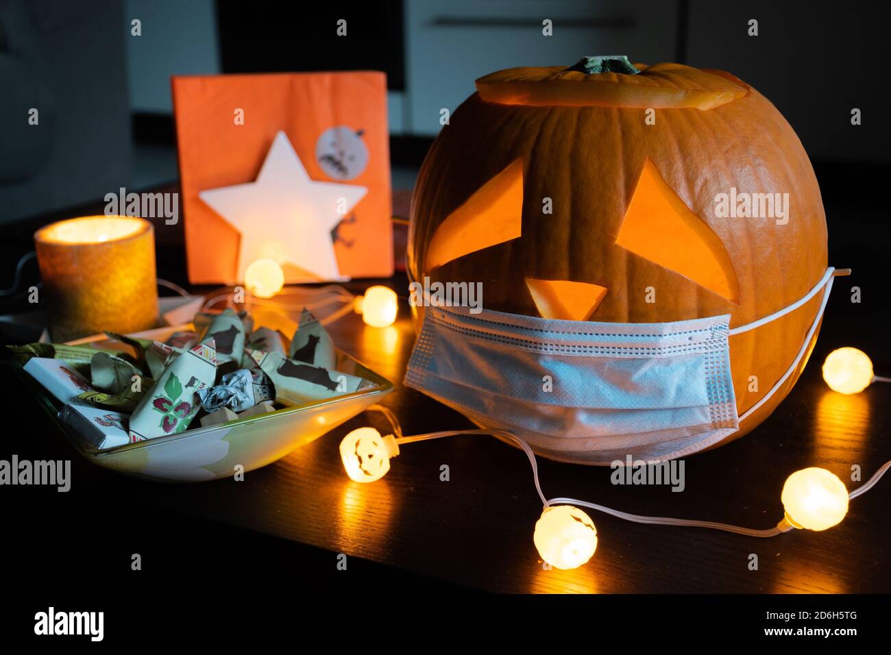 Geschnitzter Halloween Kürbis mit traurigen Augen tragen Maske, keine Party während Covid, Coronavirus Ausbruch, Ereignisse und Parteien abgesagt, um Ausbreitung zu verhindern Stockfoto