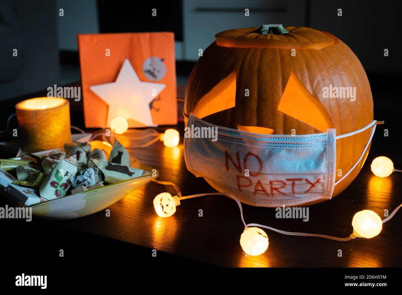 Geschnitzter Halloween Kürbis mit traurigen Augen tragen Maske, keine Party während Covid, Coronavirus Ausbruch, Ereignisse und Parteien abgesagt, um Ausbreitung zu verhindern Stockfoto