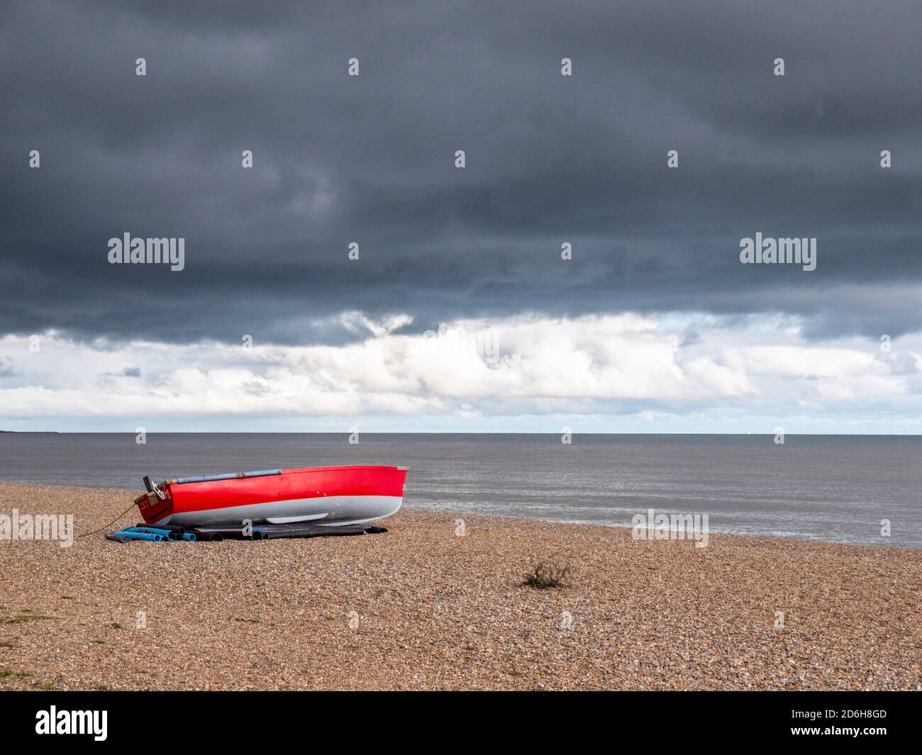 Dunwich Suffolk, Großbritannien. Oktober 2020. Ein farbenprächtiges rotes Fischerboot am Kiesstrand als ein frischer Nordwind brachte eine Mischung aus Sonnenschein und Duschen bei wechselhaftem Herbstwetter in Dunwich an der Suffolk Coast UK. Kredit: Julian Eales/Alamy Live Nachrichten Stockfoto