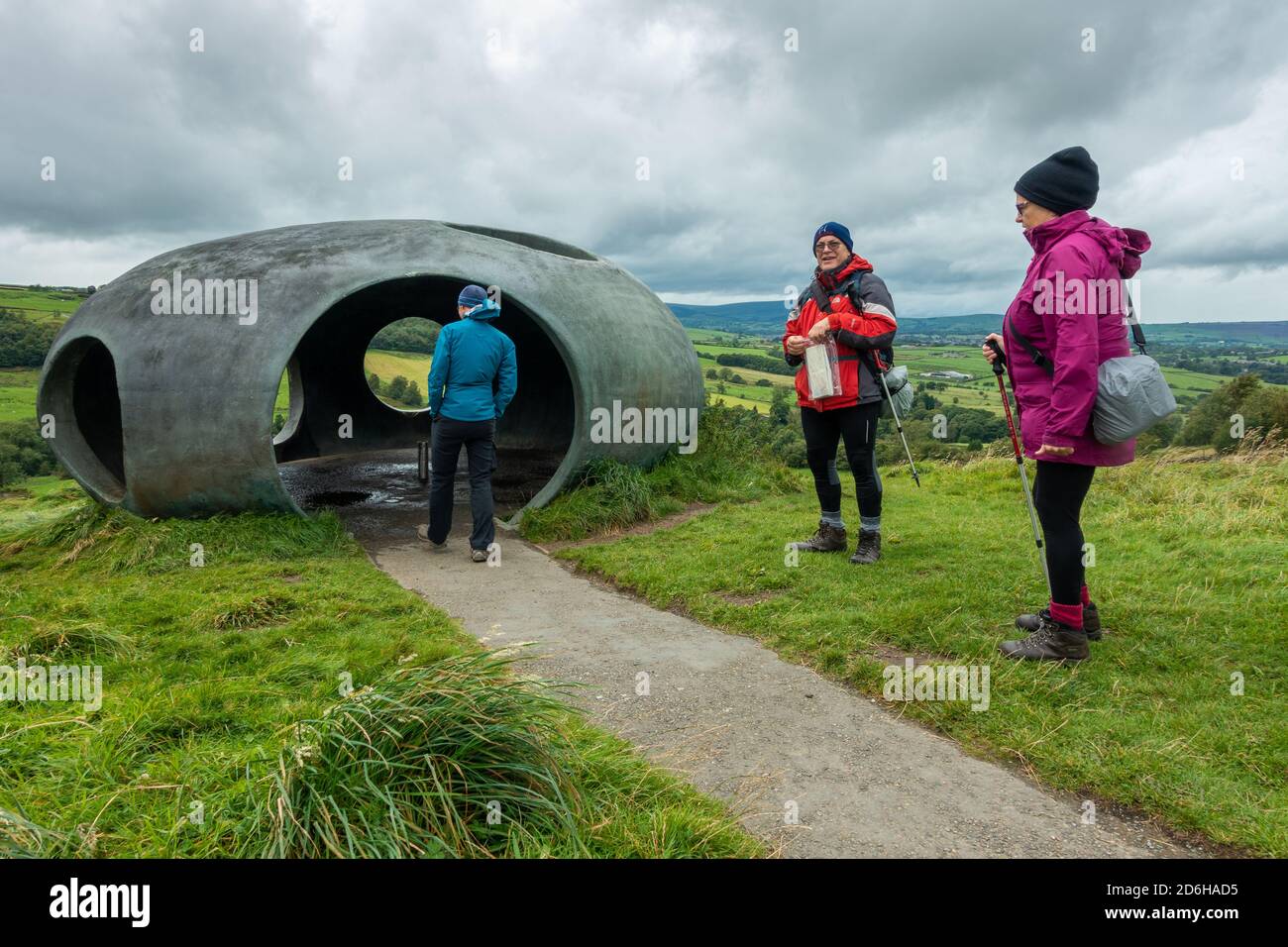 Drei Wanderer besuchen das Atom Panopticon: Eine Betonkuppel in atemberaubender Landschaft an einem regnerischen Sommertag während des Sturms Francis, Wycoller Stockfoto