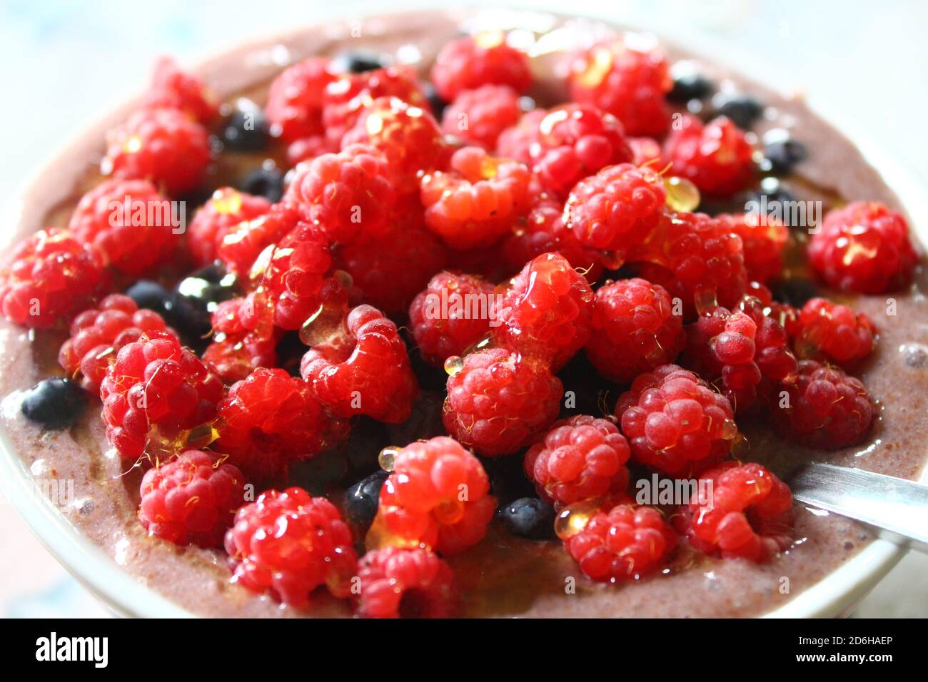 Leinsamenbrei mit Himbeeren und Heidelbeeren garniert mit Honig Stockfoto