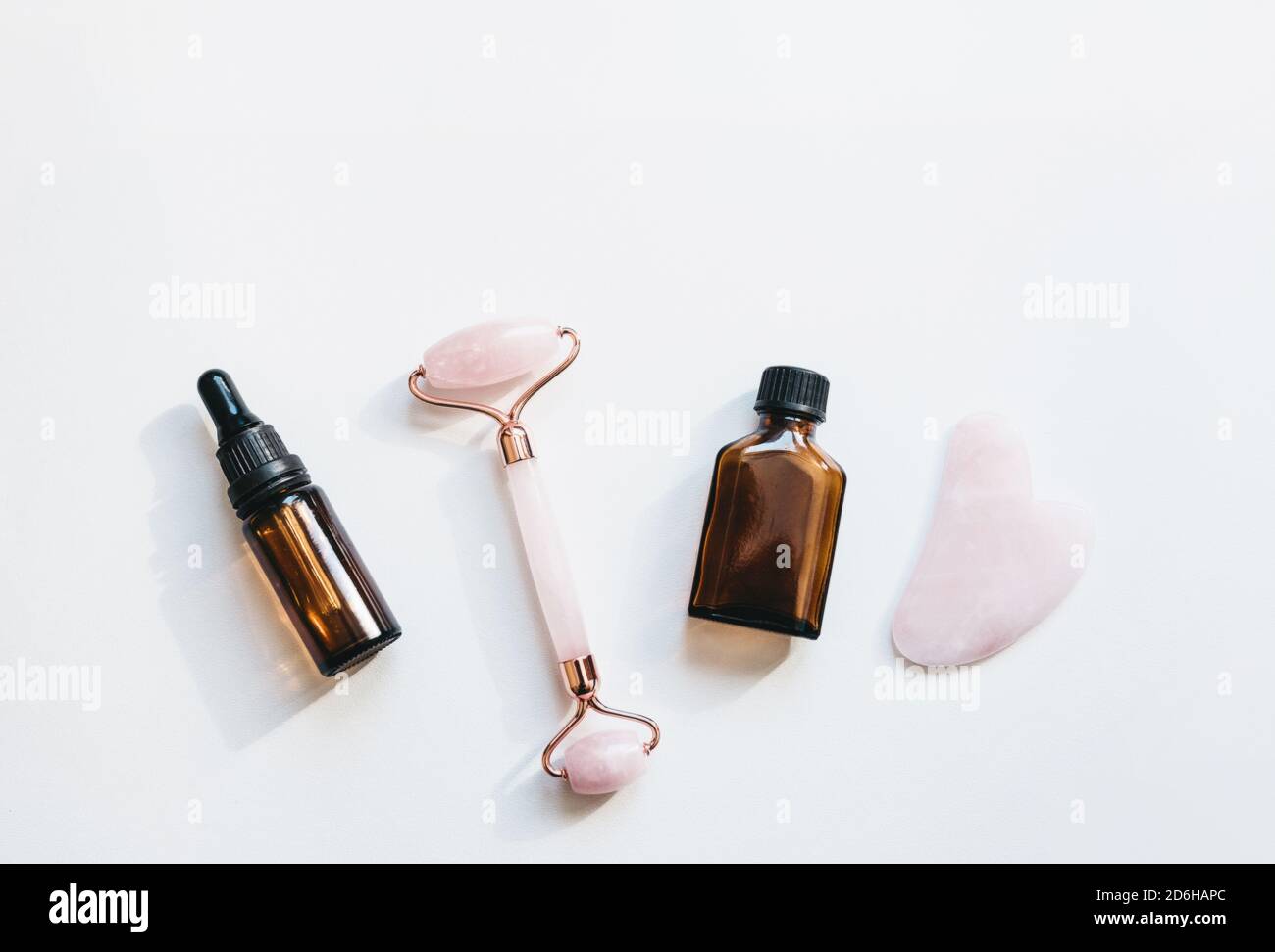 Massage-Roller, guasha und Gesichts-Serum auf weißem Hintergrund. Hautpflegeprodukte. Stockfoto