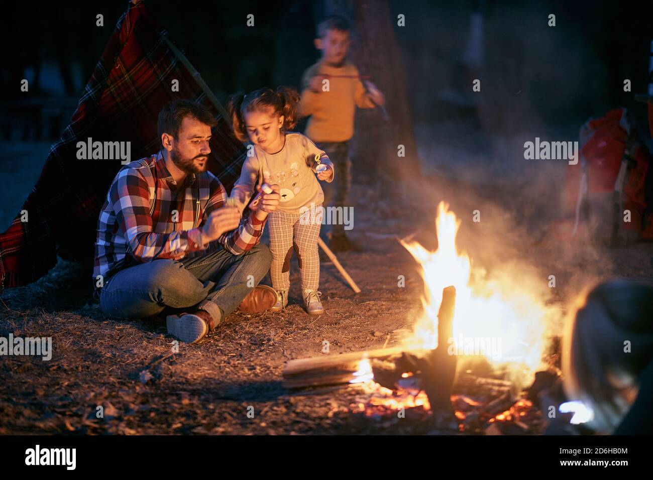 Vater und Kinder haben eine gute Zeit am Lagerfeuer in Der Wald in einer schönen Herbstdämmerung Stockfoto