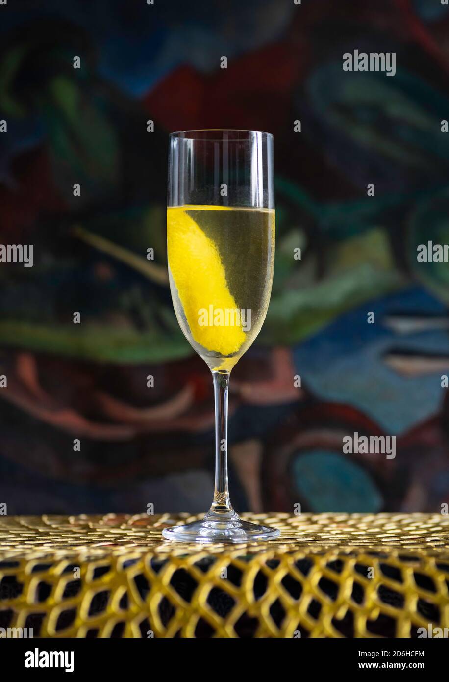 Vesper Martini Cocktail Drink mit einer Scheibe Zitrone auf einer goldenen Matte und vor einem Gemälde Stockfoto