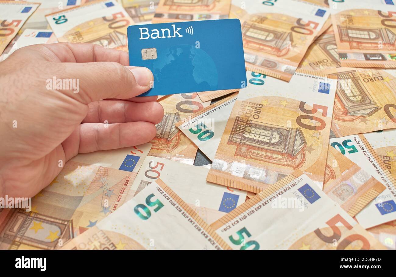 Ein weißer oder kaukasischer Mann hält in seiner Hand ein Microchiped Kredit-oder Debitkarte auf einem Hintergrund von fünfzig euro-Rechnungen Stockfoto