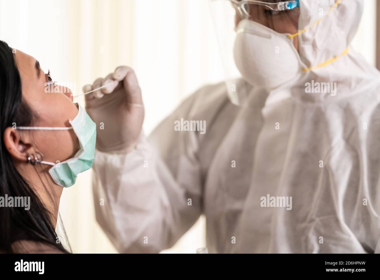Medizinisches Personal mit PPE-Anzug Test Coronavirus covid-19 an asiatische Frau durch Nasenabstrich im Hosputal. COVID-19 Prüfung Gesundheitskonzept. Stockfoto