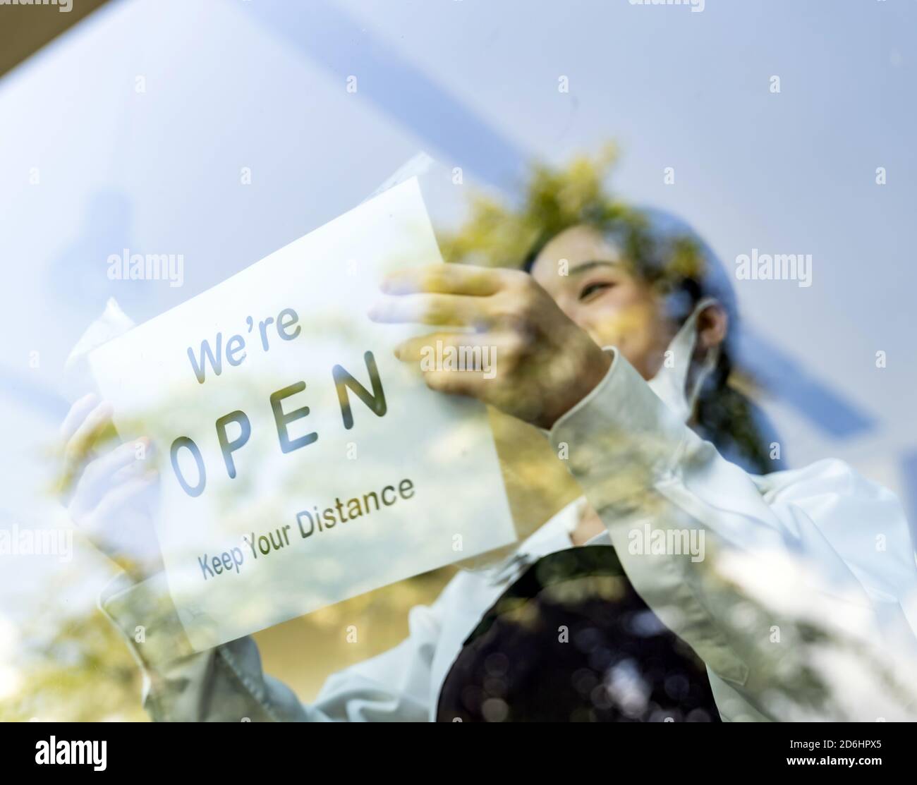 Konzentrieren Sie sich auf die Beschilderung des Restaurants. Asiatische weibliche Kellnerin setzen auf offene Beschilderung mit sozialen Abstand für neue normale Restaurant. Neue normale Restaurant-Leben Stockfoto