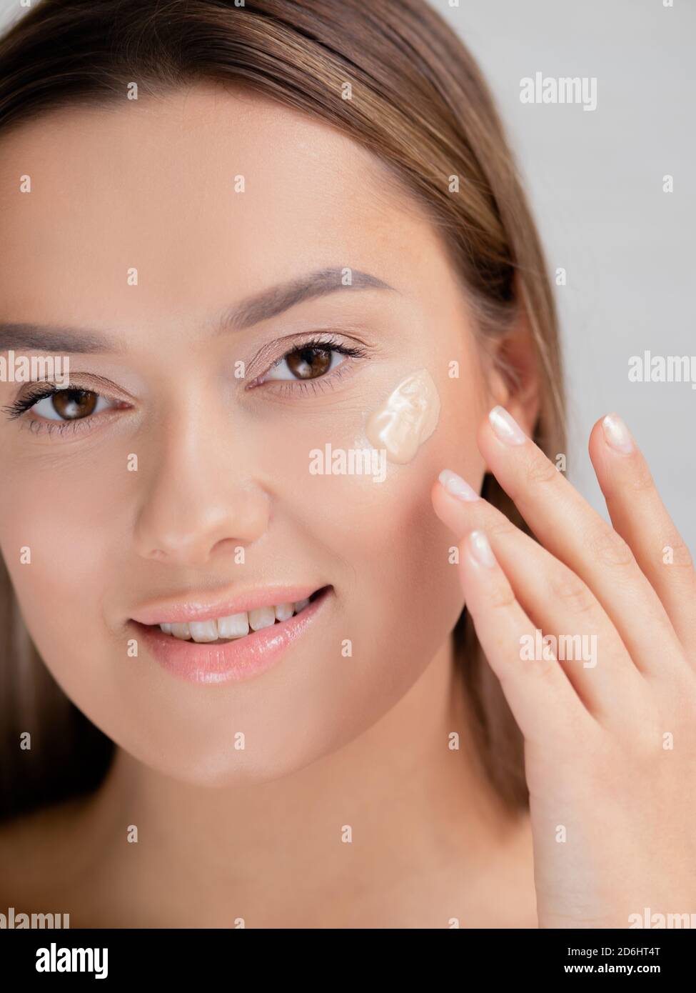 Tragen Sie die Stiftung durch Ihre Hände. Junge schöne Frau macht ihr eigenes Make-up, glatte Haut Ton, Kosmetik und Pflege. Stockfoto
