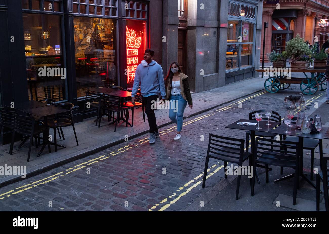 Am ersten Tag, nachdem die Stadt in Tier-2-Beschränkungen gesetzt wurde, um die Ausbreitung des Coronavirus einzudämmen, passieren Menschen leere Tische vor einem Restaurant in Covent Garden, London. Stockfoto