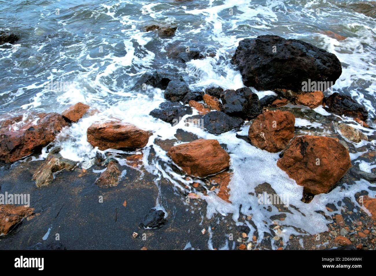 Reale Strand auf der Insel Elba. Sehr spezifisch für schwarzen Sand und rot-schwarze Steine. Stockfoto