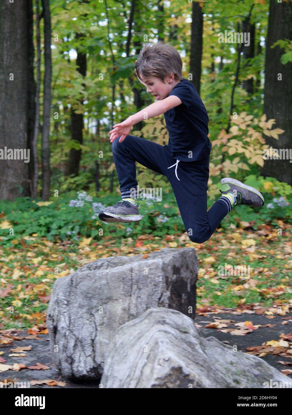 Ein athletischer 8-jähriger Junge, der hoch in die Sprünge Luft Stockfoto