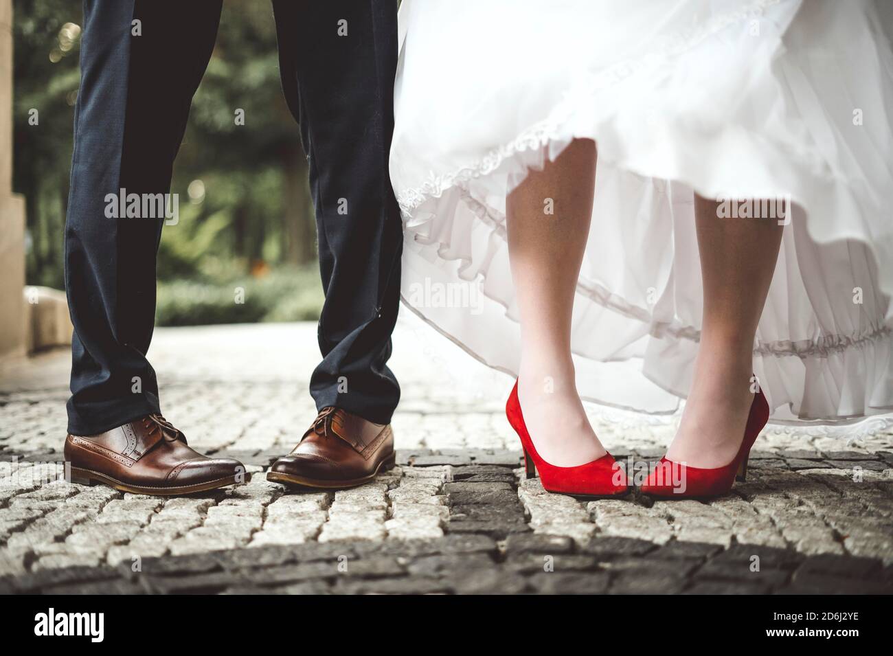 Die Beine der Braut und des Bräutigams sind nach innen gebeugt. Lustig und konzeptuell Stockfoto