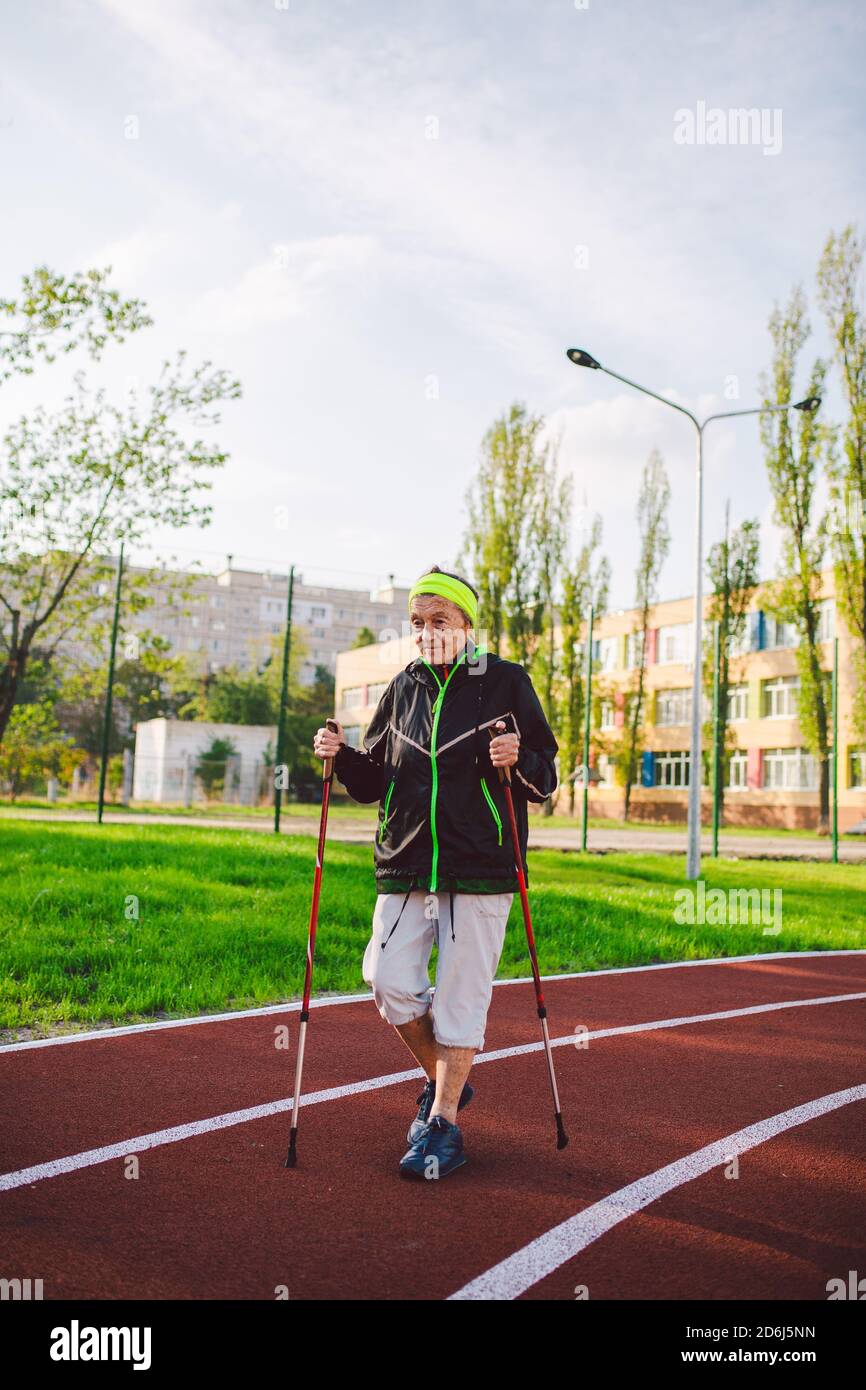 Alte Frau in Sportbekleidung übt nordic Walking im Freien auf  Gummi-Laufband im Stadion. Ältere Frauen gehen auf dem skandinavischen Weg  mit Trekkingstöcken Stockfotografie - Alamy