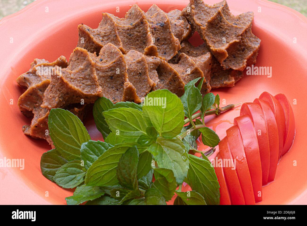 Türkische rohe Fleischbällchen (Cig kofte), türkische würzige Fleischlose mit Tomaten und Minze Food-Konzept Stockfoto