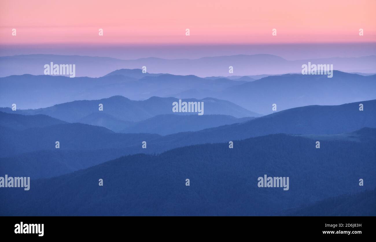 Bergrücken im Nebel bei Sonnenuntergang im Herbst. Wunderschöne Landschaft Stockfoto