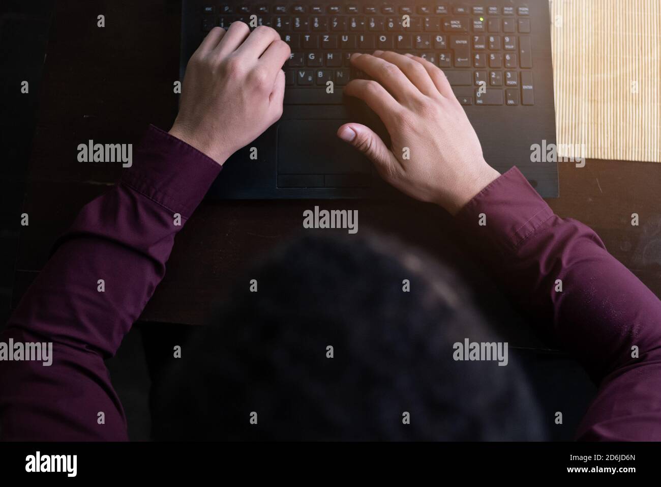 Junge schwarze männliche Entwickler sitzen in Pizza-Restaurant, trinken Kaffee oder Tee und arbeiten mit Laptop. Stockfoto