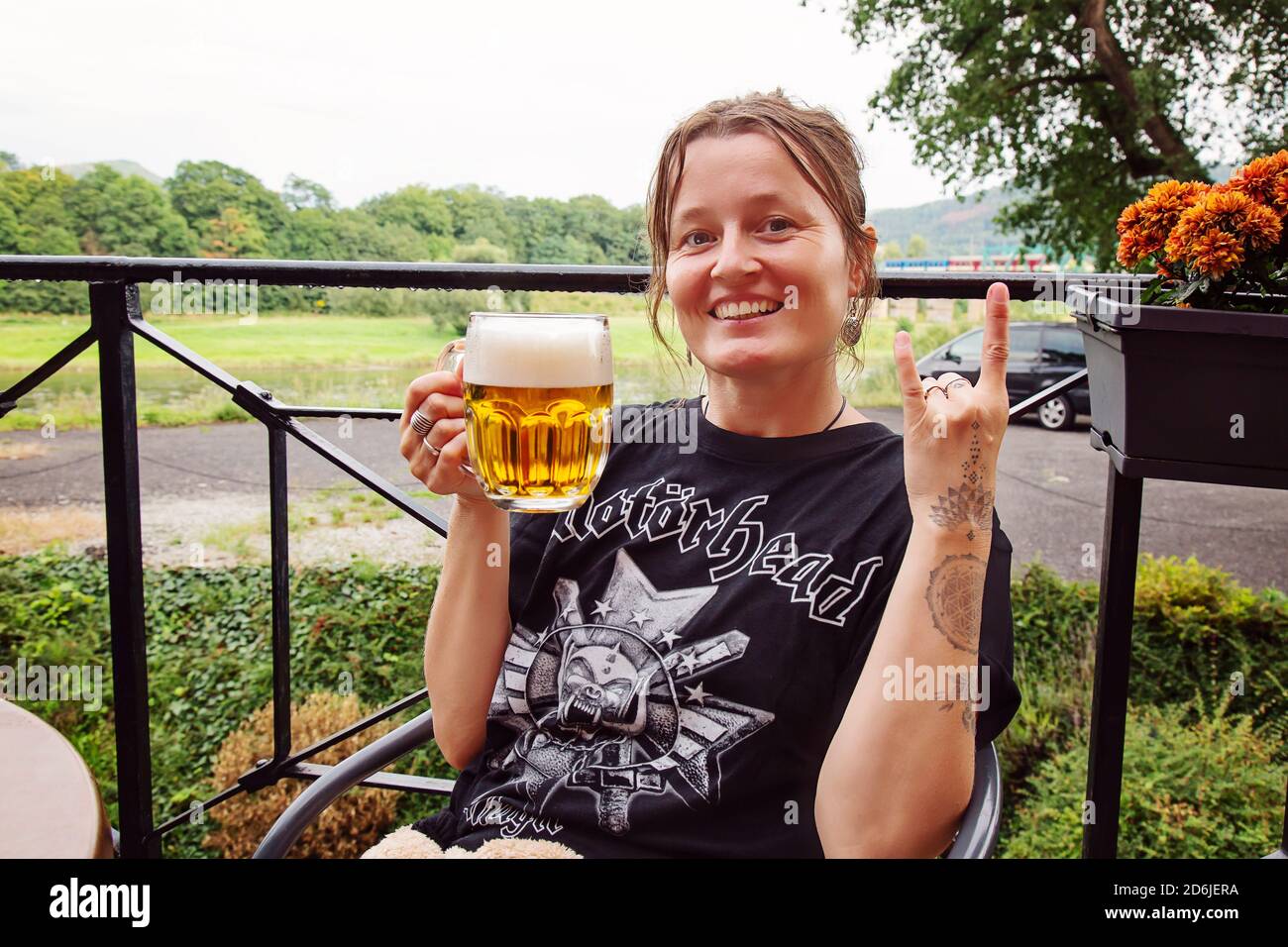 Decin, Tschechische Republik, 18. August 2020: Weibliche Motorhead Band Fan mit tschechischem Bier sitzen im Pub-Garten genießen und lächeln Stockfoto