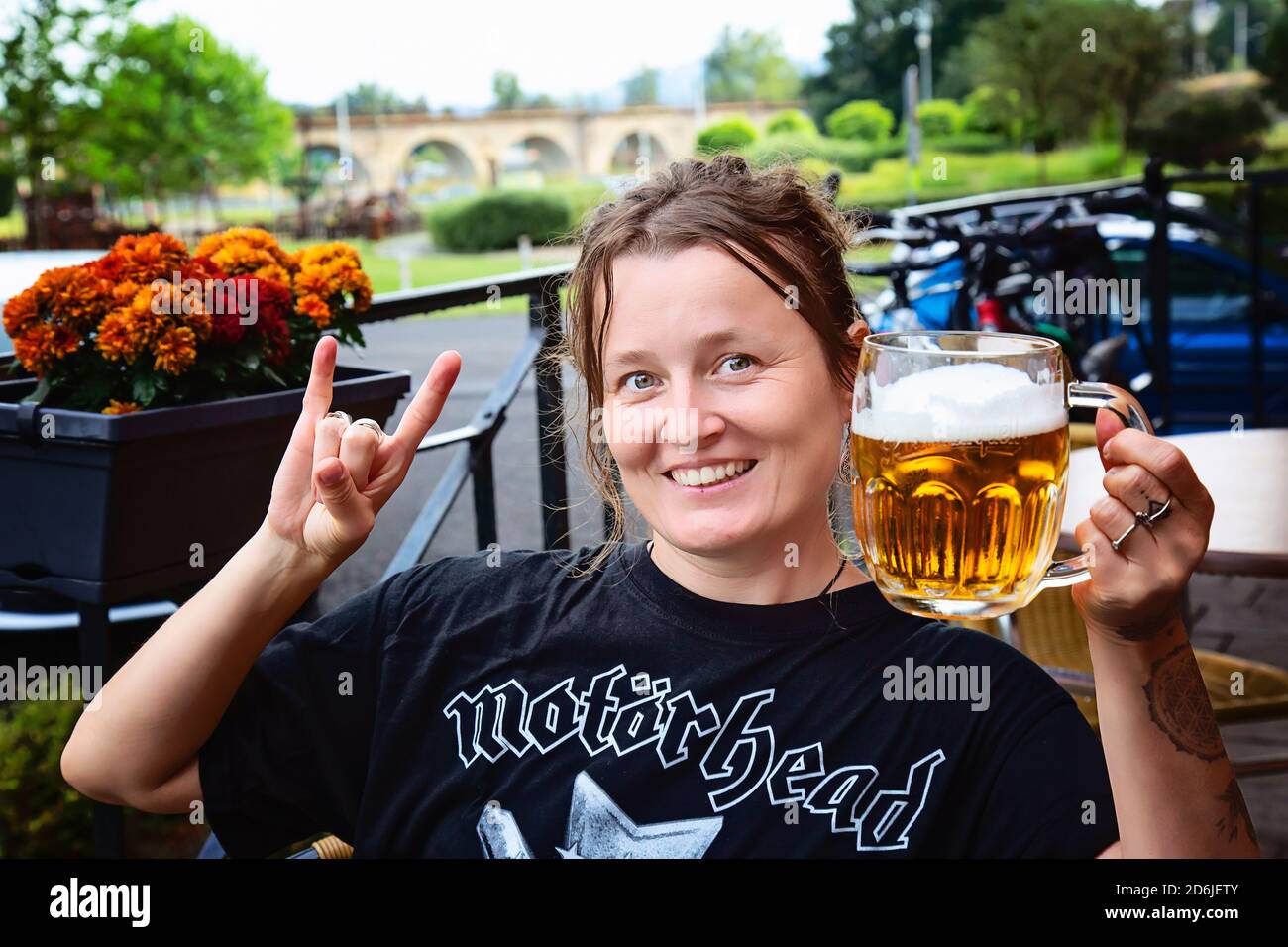 Decin, Tschechische Republik, 18. August 2020: Weibliche Motorhead Band Fan mit tschechischem Bier sitzen im Pub-Garten genießen und lächeln Stockfoto