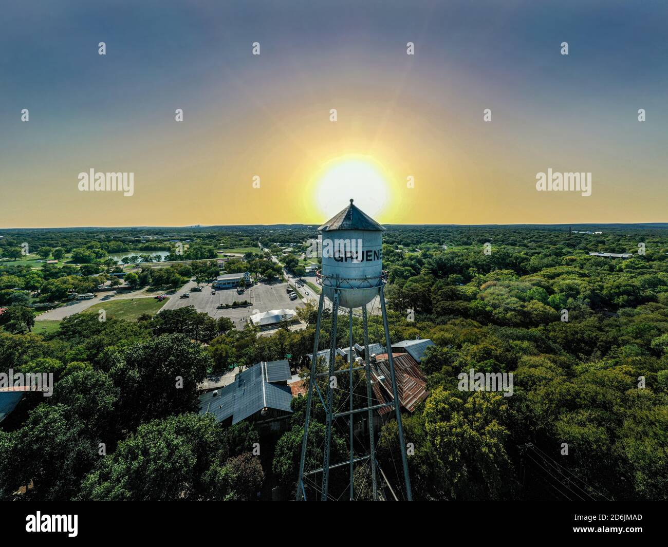 Schöner Blick auf den ikonischen Wasserturm in der Innenstadt von Gruene, TX mit dem Sonnenuntergang dahinter. Berühmte Gruene Hall und Grist Mill Restaurant sind unten. Stockfoto