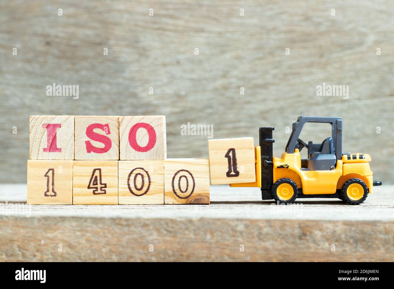 Spielzeug Gabelstapler halten Buchstabenblock 1 Wort ISO 14001 auf Holz Hintergrund zu vervollständigen Stockfoto