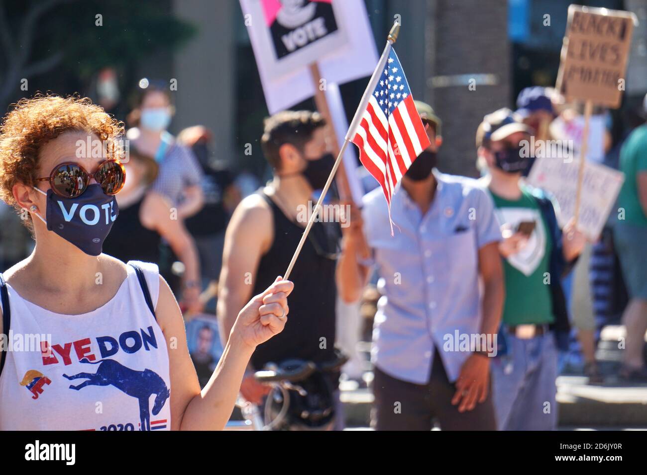 17. Oktober 2020. Marsch der Frauen in San Francisco. Biden Voter trägt Stimmmaske, ein Bye Don T-Shirt und hält kurz vor der US-Wahl eine amerikanische Flagge. Stockfoto