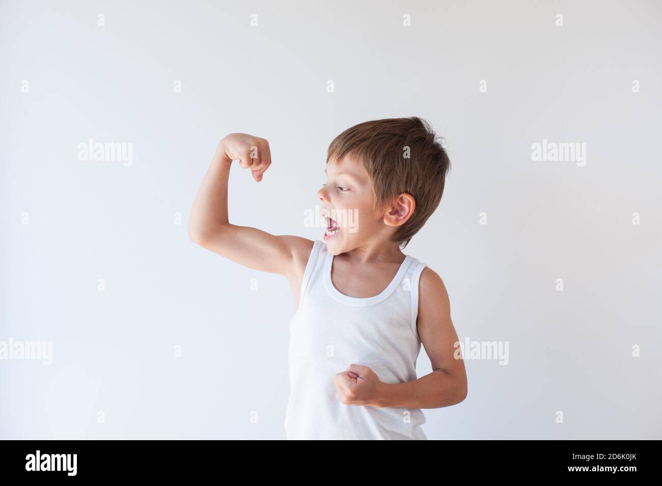 Wütend kleinen kaukasischen Kind in weißen Tank oben zeigt Muskel Auf hellem Hintergrund Stockfoto