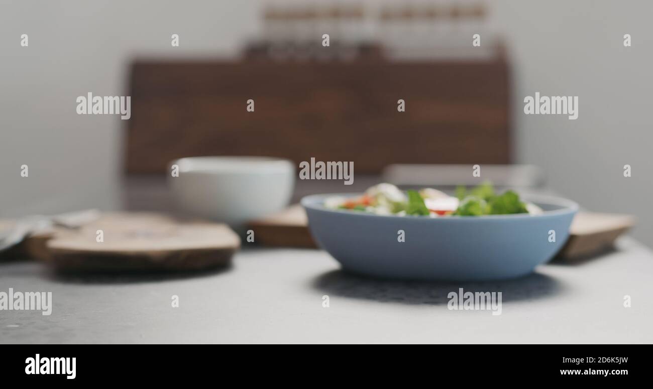 Verschwommenes Backgroiund aus Schüssel mit Salat auf Betonplatte, breites Foto Stockfoto