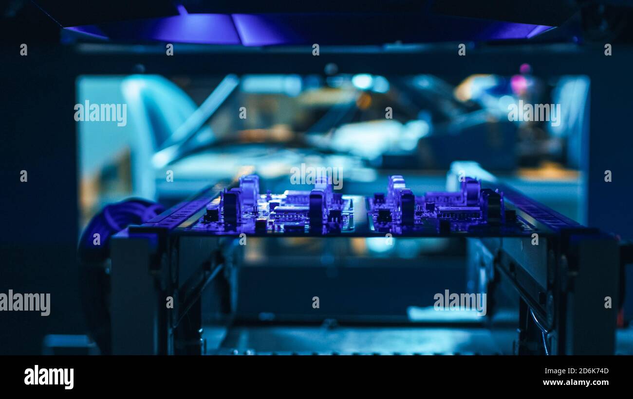 Automatisierte robotische Industrieanlagen testet elektronische Leiterplatten mit Purpule Neon Licht- und Lasertechnologie nach der Montage. Stockfoto