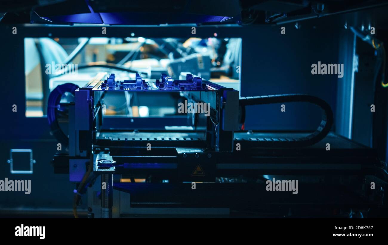 Automatisierte robotische Industrieanlagen testet elektronische Leiterplatten mit Blue Neon Light und Lasertechnologie nach der Montage. Stockfoto