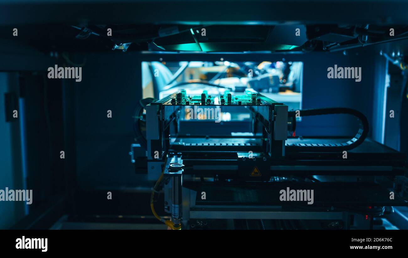 Automatisierte robotische Industrieausrüstung testet elektronische Leiterplatte und nimmt sie mit Grünlicht und Lasertechnologie nach der Montage an. Stockfoto