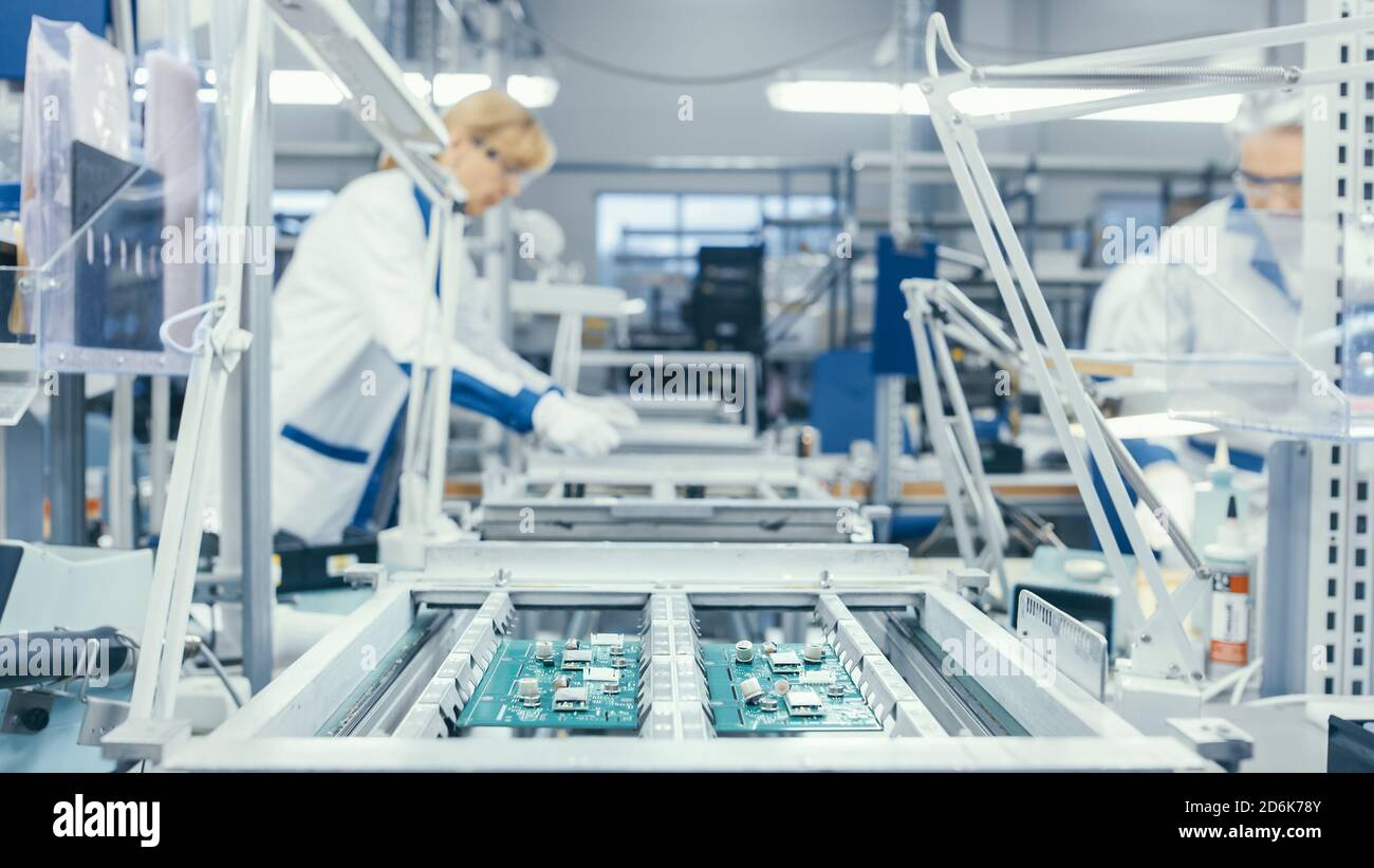 Aufnahme einer Elektronikfabrik Arbeiter Montage Leiterplatten von Hand, während es auf der Montagelinie steht. High-Tech-Fabrik. Stockfoto