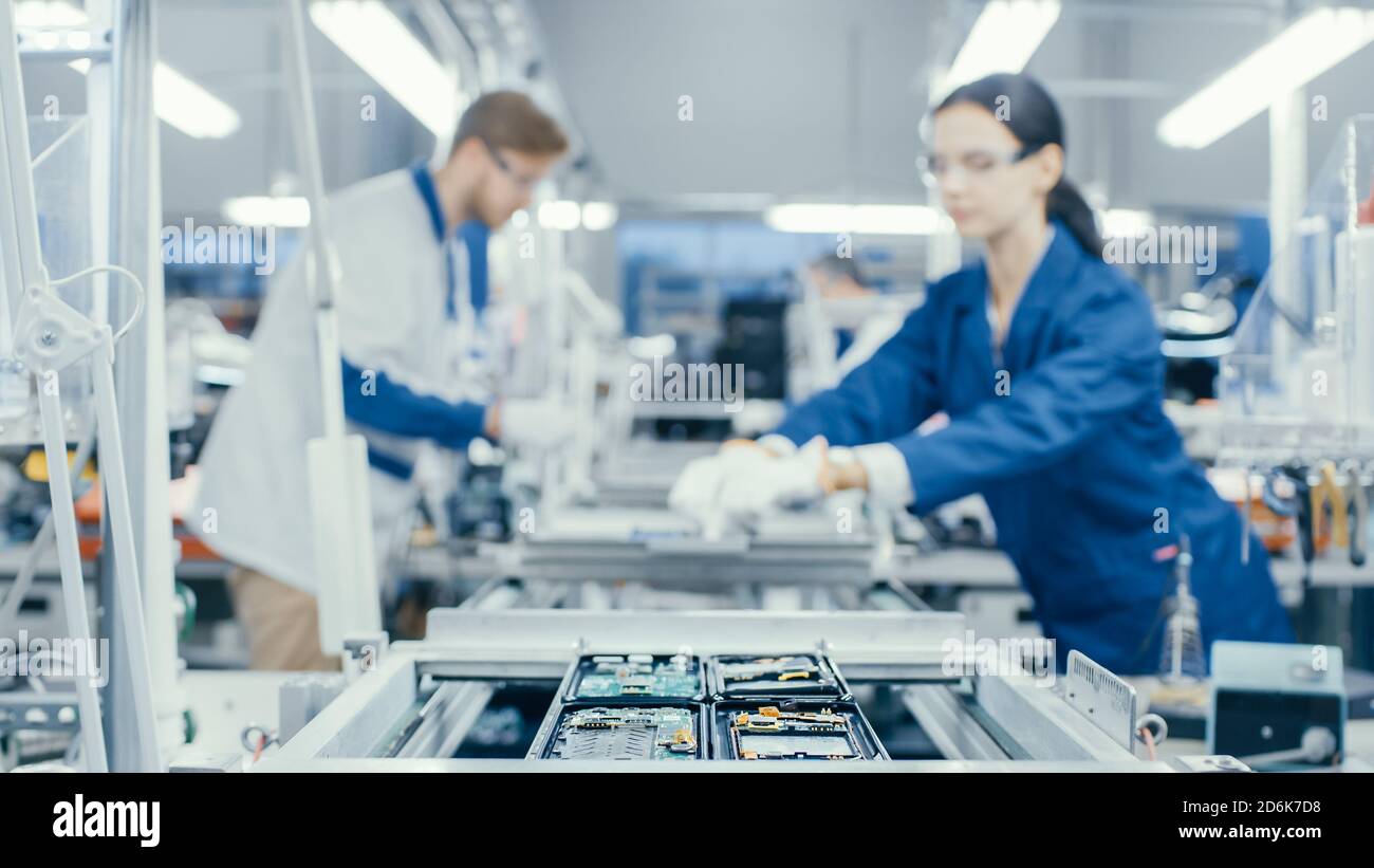 Aufnahme einer Elektronikfabrik Arbeiter Montage Leiterplatten von Hand, während es auf der Montagelinie steht. High-Tech-Fabrik. Stockfoto