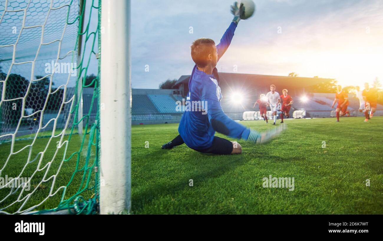 Auf Stadion Angreifer Kicks the Ball und Tore, Fußball Torwart versucht, Tore springt und fangen den Ball zu verteidigen. Aufnahme mit warmem Sonnenlicht Stockfoto