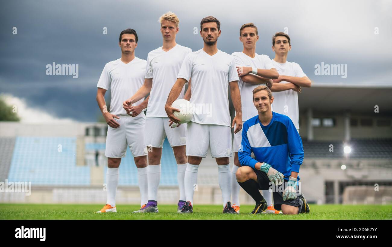 Professionelle Fußballspieler Team posiert für ein Gruppenfoto auf einem Fußballfeld stehen, Torwart sitzen und lächeln. Stockfoto