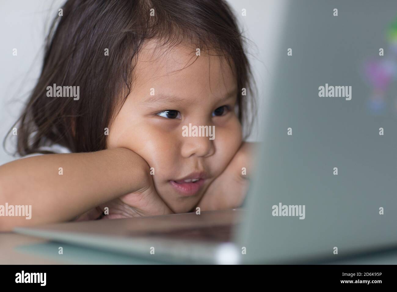 Absorbiertes junges Kind, das sich einen Film online auf einem Laptop-Computer zu Hause aus der Nähe ansieht. Stockfoto
