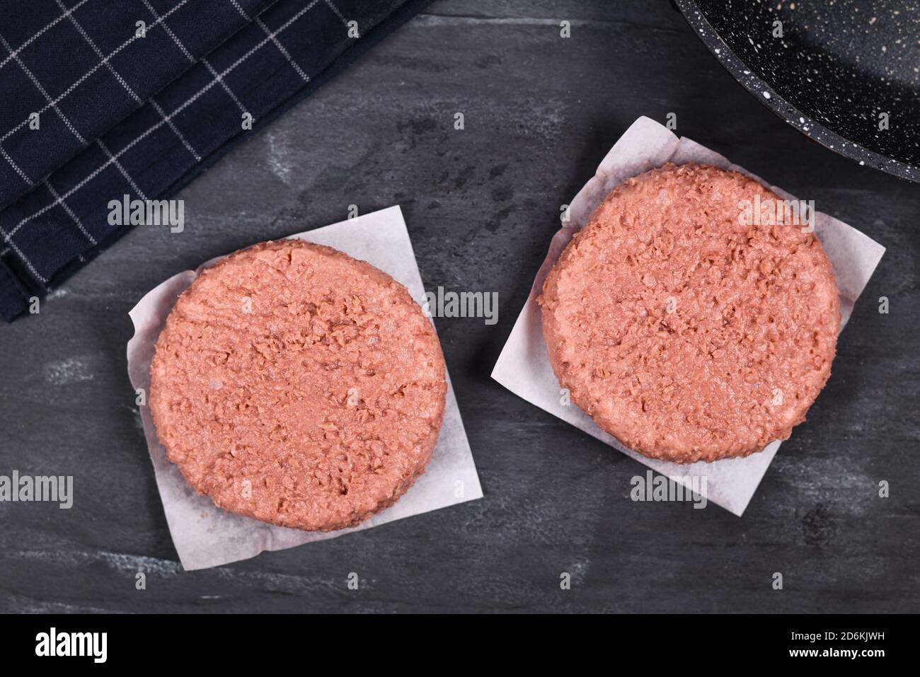 Zwei rohe runde vegane Burger-Patties auf Sojabasis auf dunklem Hintergrund Stockfoto