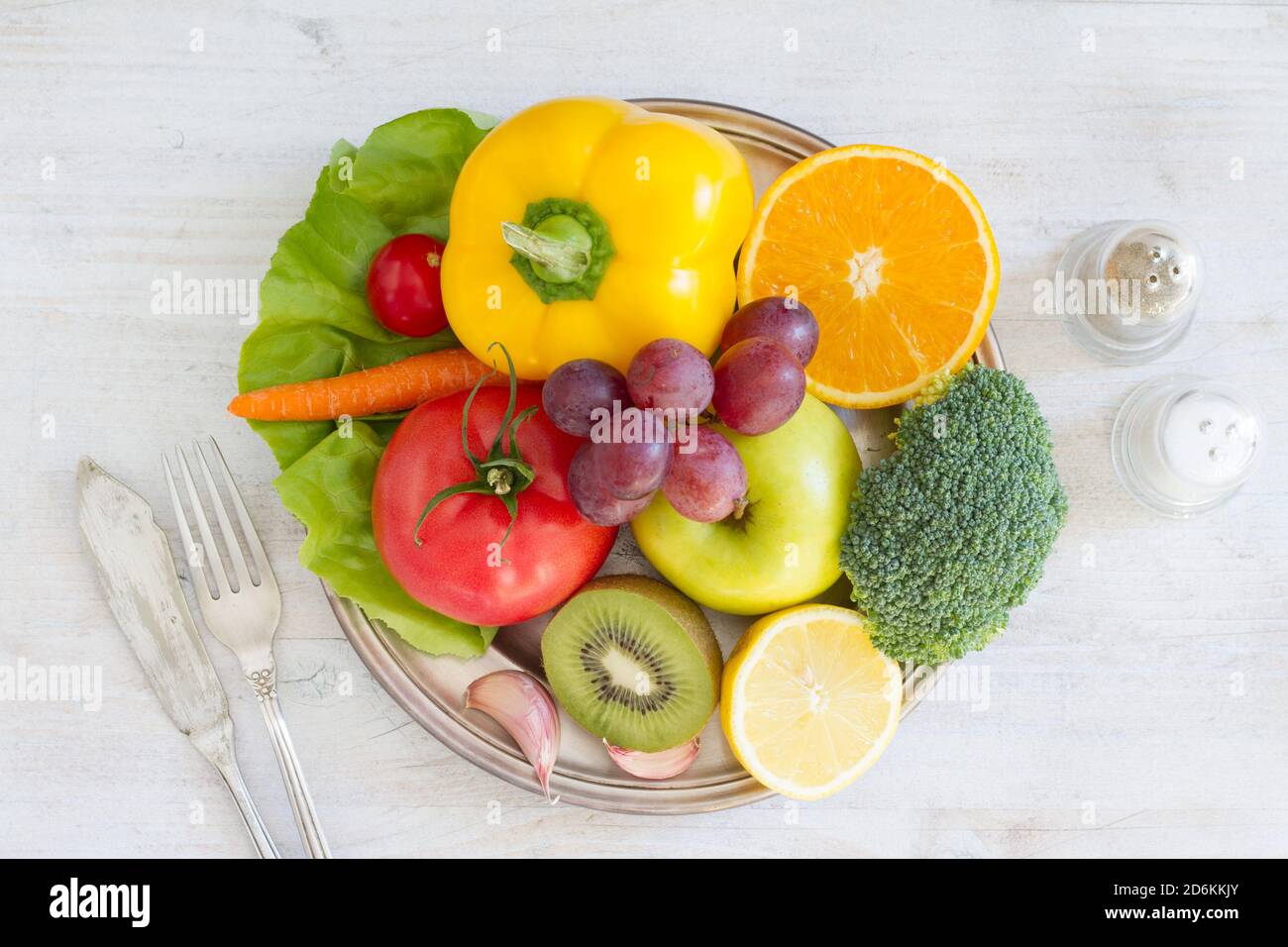 Teller voll mit Obst und Gemüse, Besteck, Gewürze. Gesundes Essen Konzept Stockfoto