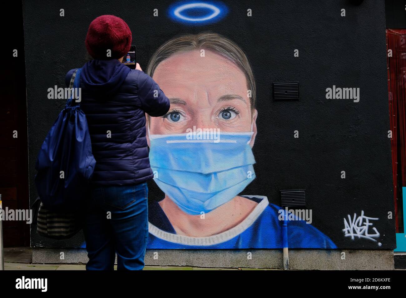 Junger Mann, der das Wandbild in der High Street in Manchester fotografiert. Krankenschwester Debra Williams als Engel von AKSE. Neue Street Art feiert NHS sie Stockfoto