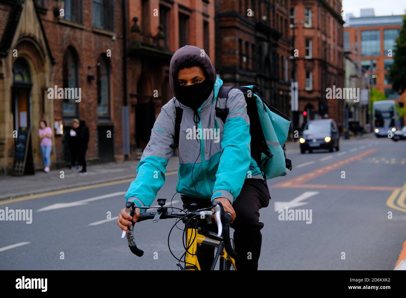 Manchester / Vereinigtes Königreich - 17. Oktober 2020: Der Lieferer mit schwarzer Gesichtsbedeckung fährt sein Fahrrad in der Manchester Street. Stockfoto