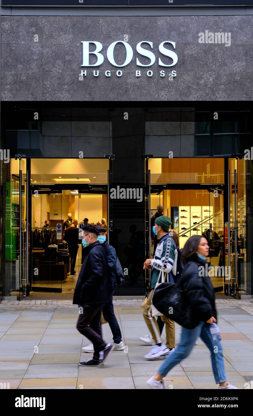 Manchester / Großbritannien - 17. Oktober 2020: Cathedral Street in Manchester mit Hugo Boss Shop Front. Verschwommene Menschen in Gesichtsmasken vorbei. Stockfoto