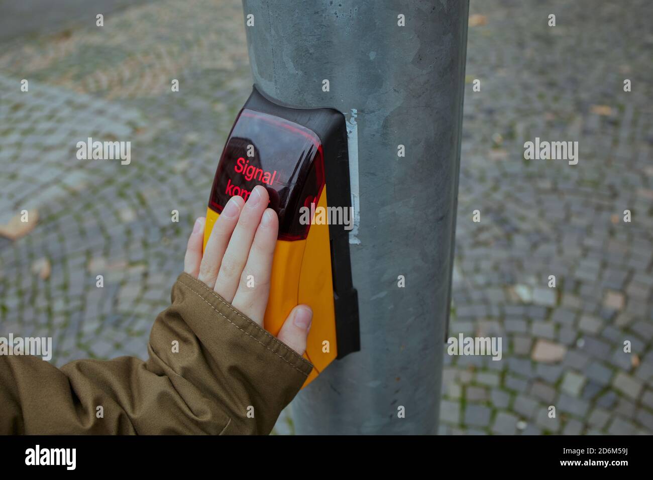 Kinderhand beim Drücken auf einen Knopf einer Ampel bedeutet das deutsche Wort Signal kommt im Englischen: Signal kommt Stockfoto